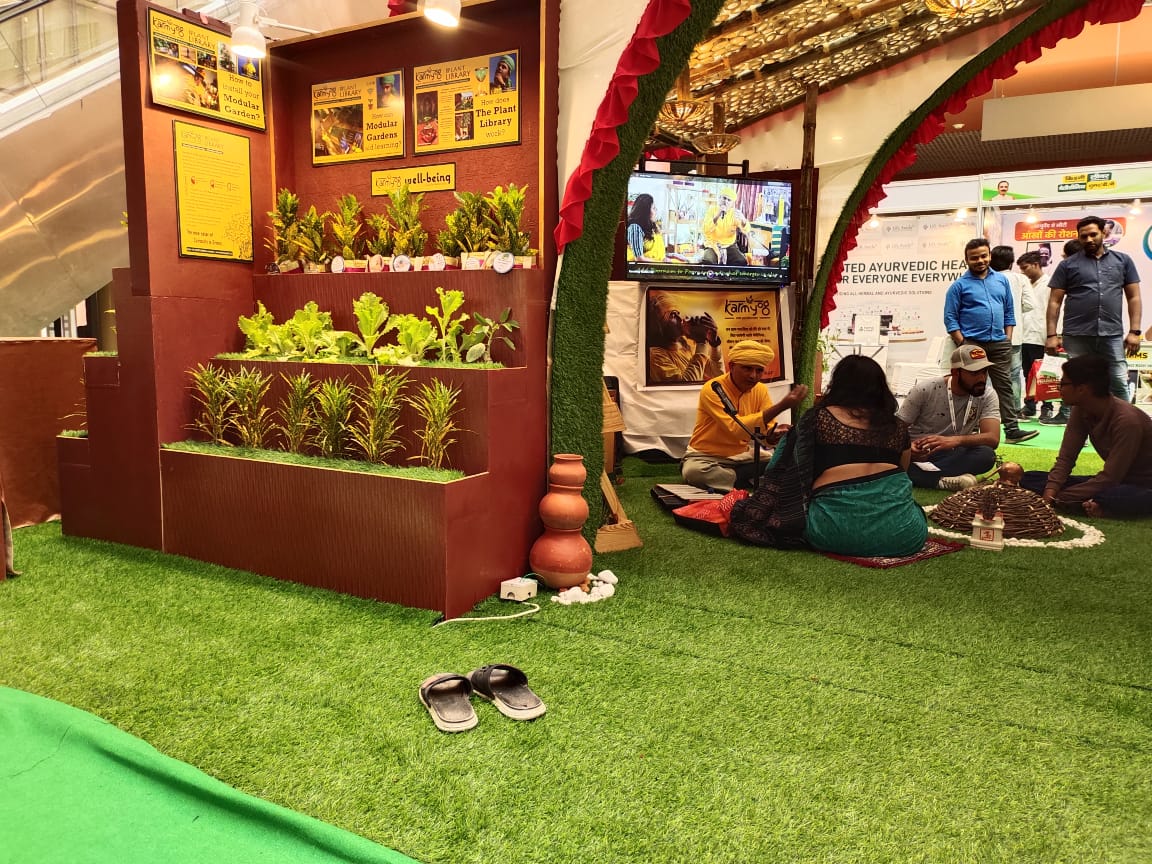 The Plant Library display wall with MahAcharyaJi sitting in conversation with a visitor