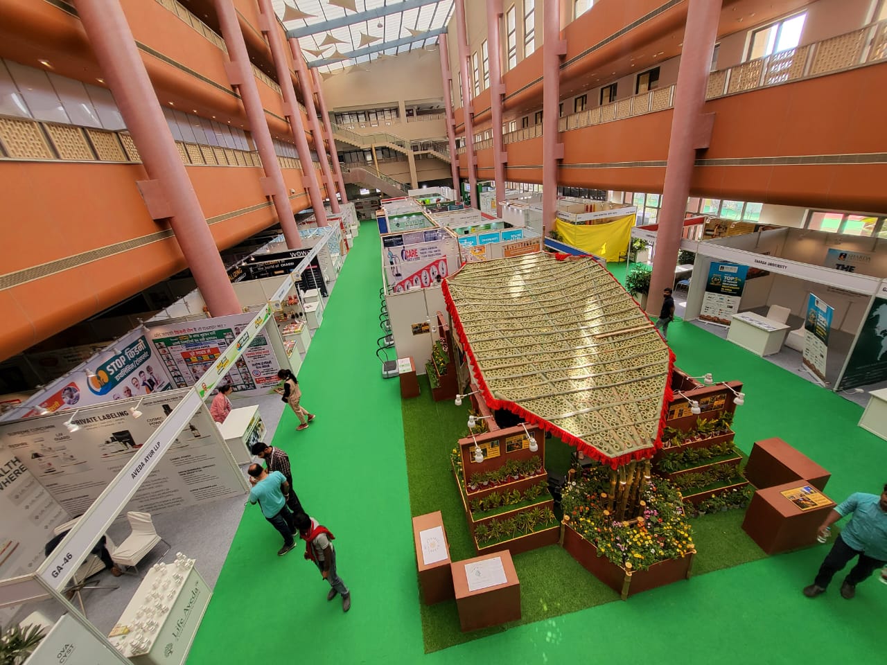 Aerial top view of the KarmYog Vatika biophilic exhibition stall standing out dramatically among standard plywood booths at AyurYog Expo 2023, Varanasi